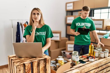 Bağışta gönüllü tişört giyen genç kadın ve erkek ciddi bir yüz ifadesiyle el pençe divan duran, kafa karıştırıcı bir fikir hakkında düşünceli bir şekilde sorular sorar. 