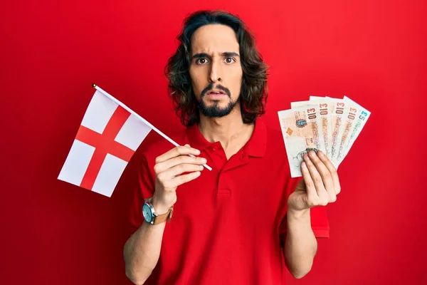 Joven Hispano Sosteniendo Bandera Inglesa Libras Billetes Sin Pistas Expresión —  Fotos de Stock