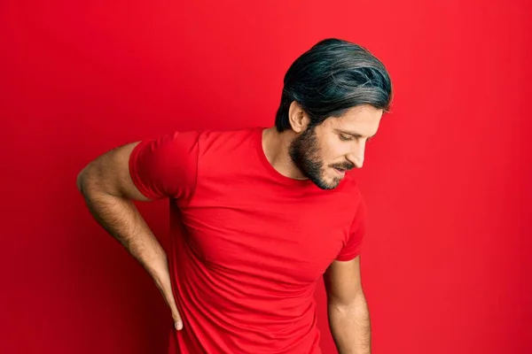 若いヒスパニック系の男は背痛の苦しんでカジュアルな赤いTシャツを着て 手で背中に触れ 筋肉痛 — ストック写真