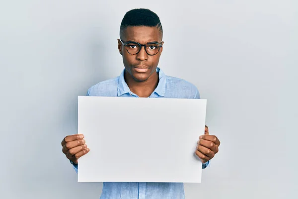 Νεαρός Αφροαμερικάνος Που Φοράει Γυαλιά Κρατώντας Ένα Κενό Πανό Σκεπτικός — Φωτογραφία Αρχείου