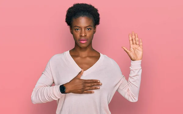 Young african american girl wearing casual clothes swearing with hand on chest and open palm, making a loyalty promise oath