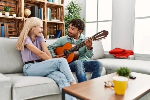 Homem Tocando Guitarra Espanhola Para Sua Namorada Sentada Sofá Casa — Fotografia de Stock