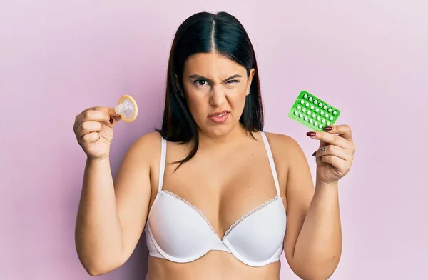 Elinde Prezervatif Doğum Kontrol Hapları Tutan Güzel Esmer Kadın Şüpheci — Stok fotoğraf