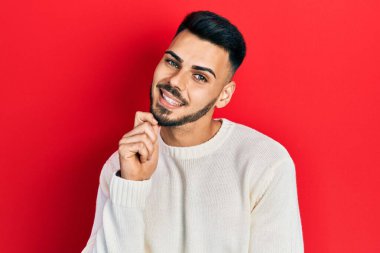 Sakallı, sıradan bir süveter giyen genç İspanyol adam kameraya kollarını kavuşturup çenesini kapatarak gülümsüyor. Olumlu düşünmek. 