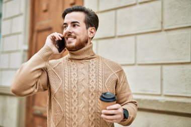 Kafkasyalı genç adam akıllı telefondan konuşuyor. Şehirde kahve içiyor..