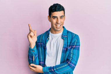 Yakışıklı, sıradan kıyafetler giyen, yüzünde kocaman bir gülümseme olan, elleri ve parmaklarıyla kameraya bakan İspanyol bir adam.. 