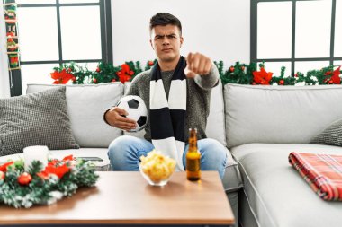 Genç İspanyol futbolcu holigan elinde top ve birayla kamerayı işaret ediyor ve kendine güvenen hareketin ciddi görünüyor. 