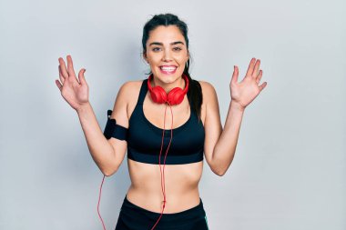 Spor kıyafetleri giyen ve kulaklık takan genç İspanyol kız on numarayı gösterip işaret ederken kendinden emin ve mutlu bir şekilde gülümsüyor.. 