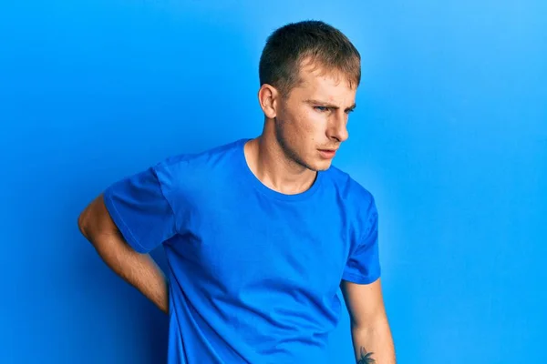 背痛の苦しみ 手で背中に触れる 筋肉痛 カジュアルブルーのTシャツを着て若い白人男性 — ストック写真