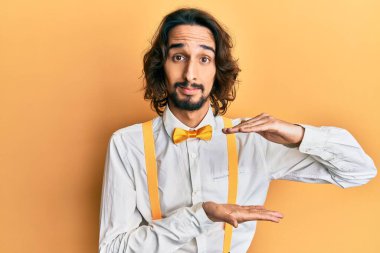 Genç, İspanyol asıllı, hippi görünümlü, zarif görünümlü, elleri büyük ve büyük bir işaret gösteren, ölçü sembolü olan bir adam. Kameraya bakıp gülümsüyor. ölçüm kavramı. 