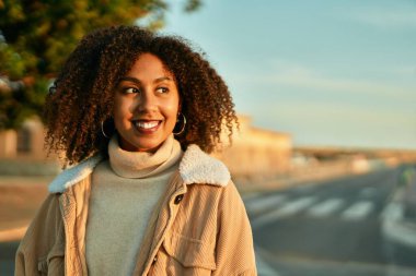 Genç Afrikalı Amerikalı kadın gülümseyerek şehirde mutlu mesut duruyor..
