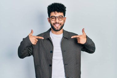 Sakallı, gözlüklü, kendine güvenen, gülümseyen, kendini gururlu ve mutlu gösteren genç bir Arap.. 