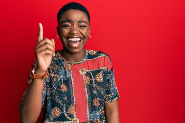 Afro-Amerikan tarzı giyinmiş genç bir Afro-Amerikan kadını başarılı bir fikirle işaret ediyor. Heyecanlı ve mutlu. Bir numara.. 