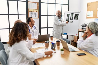 Bir grup orta yaşlı doktor klinikteki bir tıbbi toplantıda tartışıyorlar..