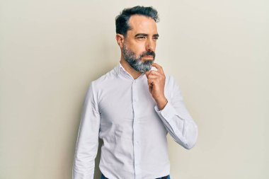 Sakallı ve gri saçlı orta yaşlı bir adam günlük beyaz gömlek giyiyordu. Düşünceleri şüphe üzerine yoğunlaşmıştı. Parmakları çenesinde ve yukarı bakıyordu. 