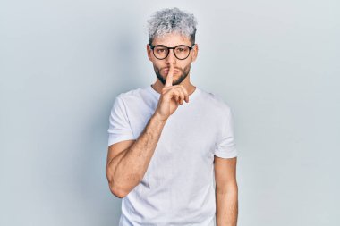 Modern boyalı saçlı, beyaz tişörtlü ve gözlüklü dudaklı, sessiz olmak isteyen genç bir İspanyol. sessizlik ve gizli konsept. 