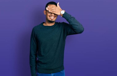 Gündelik kıyafetler ve gözlük takan, gülümseyen ve gülen genç Afro-Amerikan erkeği şaşırtmak için gözlerini kapatıyor. kör kavram. 