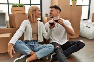 Kırmızı şarap kadehleriyle kadeh kaldıran beyaz bir çift yeni evlerinde oturuyor..