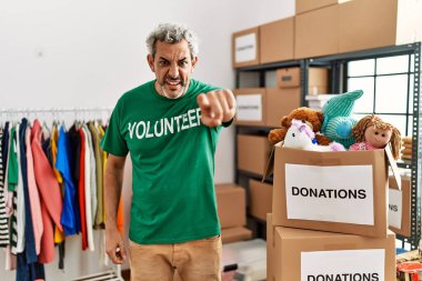 Bağışta gönüllü tişört giyen orta yaşlı İspanyol adam kameraya kızgın ve sinirli bir şekilde bakıyor. 