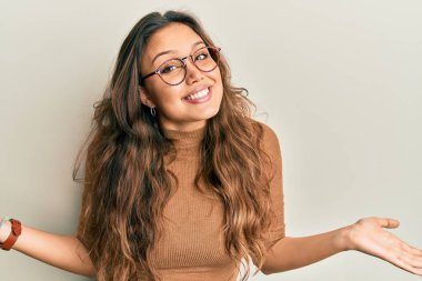 Gündelik kıyafetler ve gözlük takan genç İspanyol kız gülümseyerek iki elini de açık tutuyor, sunuyor ve reklam karşılaştırması yapıyor ve dengeyi sağlıyor. 