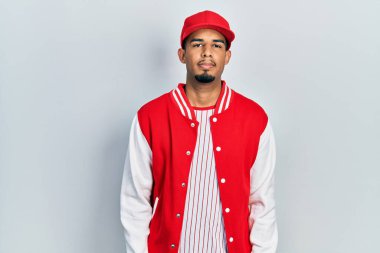 Beyzbol üniforması giyen genç Afro-Amerikan adam yüzünde ciddi bir ifadeyle rahatladı. Basit ve doğal bir şekilde kameraya bakıyorsun.. 