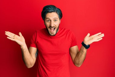 Sıradan kırmızı tişört giyen genç İspanyol adam çılgınlığı kutluyor ve başarıya hayret ediyor kolları açık ve gözleri açık heyecanla bağırıyor. Kazanan konsept 