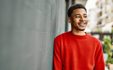 Yakışıklı Afro-Amerikan adam gri duvarın üzerinde duruyor.