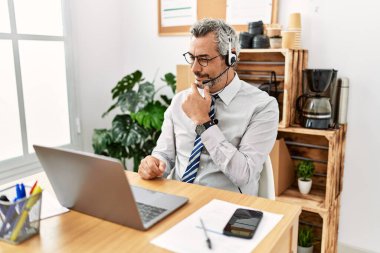 Ofiste çalışan İspanyol bir işadamı operatör kulaklığı takıyor kameraya kollarını kavuşturup gülümseyerek bakıyor ve çenesini kaldırıyor. Olumlu düşünmek. 