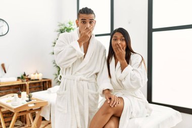 Güzellik merkezinde havluyla dikilen genç latin çift yanlışlıkla ağızlarını kapatıyorlar. gizli kavram. 