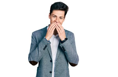 İş kıyafetleri giymiş genç İspanyol adam gülüyor ve utanıyor kıkırdıyor elleriyle ağzını kapatıyor, dedikodu yapıyor ve skandal konsepti yapıyor. 