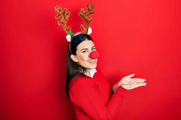 Mladá Hispánka Nosí Jelení Vánoční Klobouk Červený Nos Ukazuje Stranou — Stock fotografie