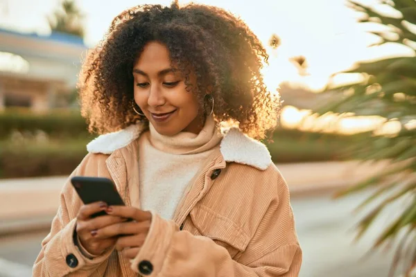 若いアフリカ系アメリカ人の女性が市内のスマートフォンを使って笑顔で — ストック写真