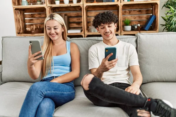 Pareja Joven Usando Teléfono Inteligente Sentado Sofá Casa —  Fotos de Stock