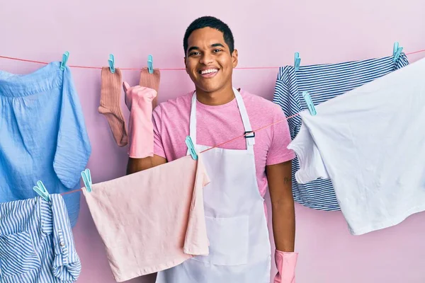 Jovem Homem Hispânico Bonito Vestindo Avental Limpo Segurando Roupas Varal — Fotografia de Stock