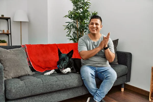 Jovem Latino Homem Cão Sentado Sofá Casa Aplaudindo Aplaudindo Felizes — Fotografia de Stock