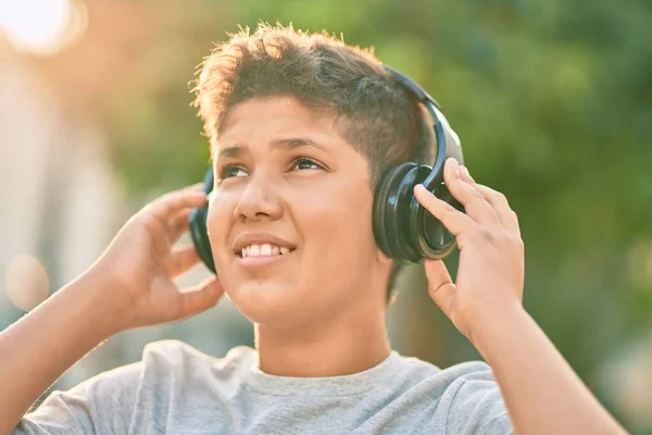 城市里可爱的拉丁男孩用耳机高兴地微笑着 — 图库照片