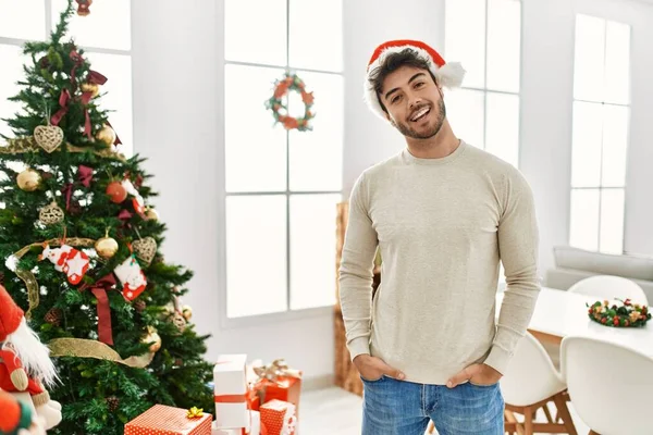 Ung Latinamerikansk Man Ler Glad Bär Jul Hatt Står Hemma — Stockfoto