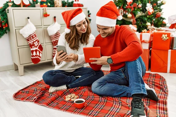 Jovem Casal Hispânico Usando Chapéu Natal Usando Touchpad Smartphone Sentado — Fotografia de Stock