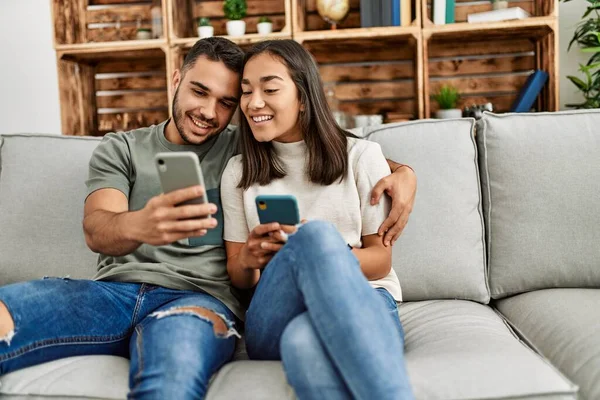 Evdeki Kanepede Oturan Akıllı Telefon Kullanan Genç Latin Çift — Stok fotoğraf