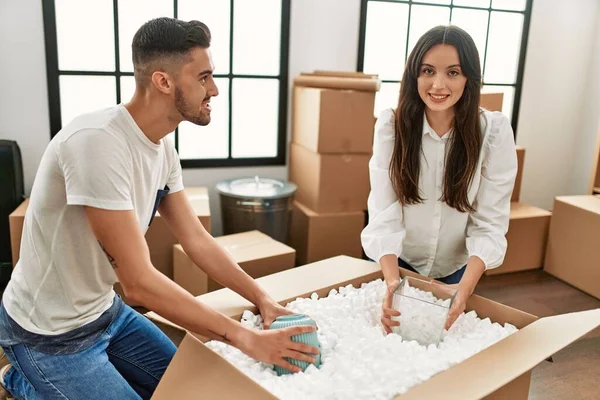 Jovem Casal Hispânico Sorrindo Feliz Desembalagem Caixa Papelão Nova Casa — Fotografia de Stock