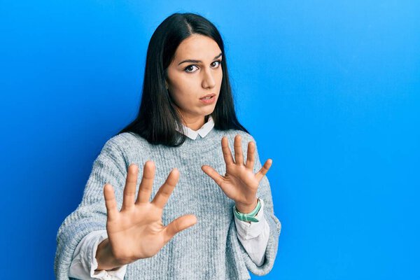 Young hispanic woman wearing casual clothes moving away hands palms showing refusal and denial with afraid and disgusting expression. stop and forbidden. 