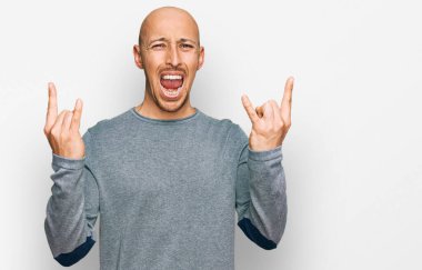 Kel, sakallı, günlük kıyafetler giyen, çılgın bir ifadeyle bağıran, elleri havada rock sembolü yapan bir adam. Müzik yıldızı. ağır kavram. 