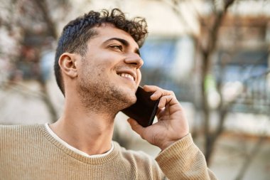 Genç İspanyol adam gülümsüyor. Şehirdeki akıllı telefondan konuşuyor.