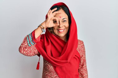 Orta yaşlı İspanyol kadın geleneksel Sherwani sari giysisi giyiyor. El hareketleriyle gülümsüyor, gözleriyle mutlu yüzlere bakıyor.. 