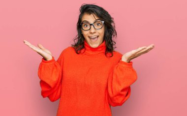 Gündelik kıyafetler ve gözlük takan genç İspanyol kadın zaferi mutlu bir gülümsemeyle kutluyor ve kazanan yüz ifadesi kaldırıyor. 