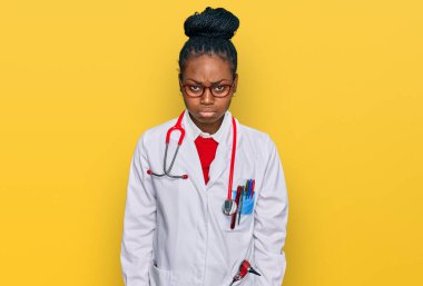 Genç Afro-Amerikalı kadın doktor üniforması ve steteskop giyiyor. Depresyonda ve endişe içinde, kızgın ve korkmuş bir şekilde ağlıyor. hüzünlü ifade. 