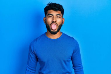 Sakallı, sıradan mavi süveter giyen, dilini komik bir ifadeyle dışarı çıkaran bir Arap. duygu kavramı. 