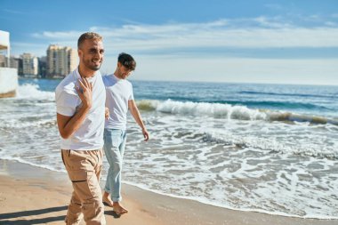 Genç eşcinsel çift mutlu bir şekilde sahilde yürüyor..