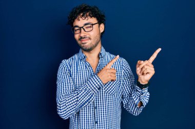 Gündelik kıyafetler giyen, gözlüklü, gülümseyen ve kameraya bakan genç İspanyol bir adam.. 