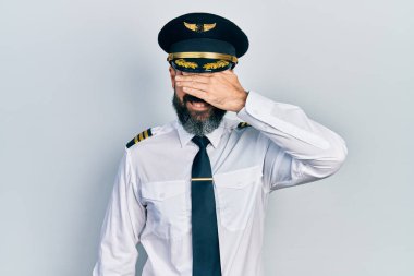 Uçak pilotu üniforması giyen genç İspanyol bir adam. Gülümsüyor ve elleri yüzünde gülüyor. Şaşırtmak için gözleri örtüyor. kör kavram. 